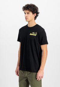 Čierne bavlnené tričko s okrúhlym výstrihom a krátkymi rukávmi, so žltým nápisom "Hawaii" a malým grafickým dizajnom na prednej strane.