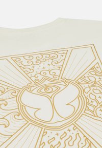 Crème-kleurig stoffen T-shirt met een ingewikkeld gouden gedrukt ontwerp met een centraal oog en bloemmotieven, verfraaid met draaipatronen en stralen.