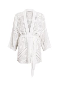 Veste style kimono en dentelle blanche avec motifs floraux, manches larges, devant ouvert et ceinture assortie en tissu nouée à la taille.