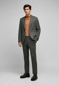 Grijs gestructureerd pak met subtiel ruitpatroon, bruine coltrui en donkerbruine veterschoenen. Gepersonaliseerde pasvorm en gestructureerd ontwerp.