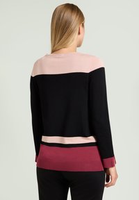 Gestrickter Pullover mit schwarzem Hauptkörper, hellrosa oberen Einsätzen und einem bordeauxroten unteren Streifen mit horizontalen Streifen. Gerippte Bündchen und Saum.