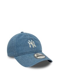 Modra denim kapa za bejzbol z nastavljivim trakom, ki ima krožni logotip in belo vezeno "NY" na sprednji strani. Enostavna, teksturirana tkanina.
