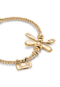 Bracelet doré mettant en vedette un charm libellule avec des ailes lisses et arrondies et un design de perles texturées, ainsi qu'une petite étiquette gravée.