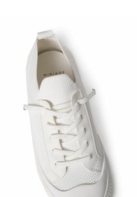 Hvide sneakers med et tekstureret stofoverdel, glatte læderdetaljer, rund tå og flade snørebånd. Har en løftestrop ved hælen.