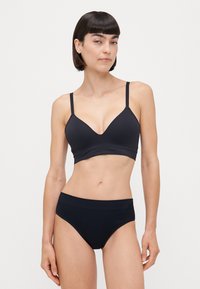 Melnas apakšveļas komplekts ar bezvadu trīsstūra krūšturi ar plānām siksnām un atbilstošām augsto vidukli biksēm. Gluda auduma tekstūra.