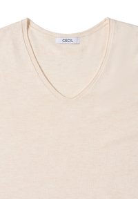 Beige V-Ausschnitt T-Shirt aus weichem, leichtem Stoff. Hat ein schlichtes Design mit einem Etikett, das "CECIL" in der Nähe des Halsausschnitts anzeigt.