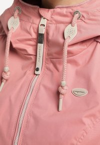 Roze hoodie met een voorrits, textuurstof en decoratieve koordjes. Bevat een rond logo en opvallende stikdetails.