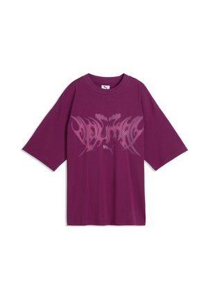 T-shirt oversize violet avec un motif rose style tribal et un logo Puma blanc centré sur la poitrine, manches courtes et col rond.