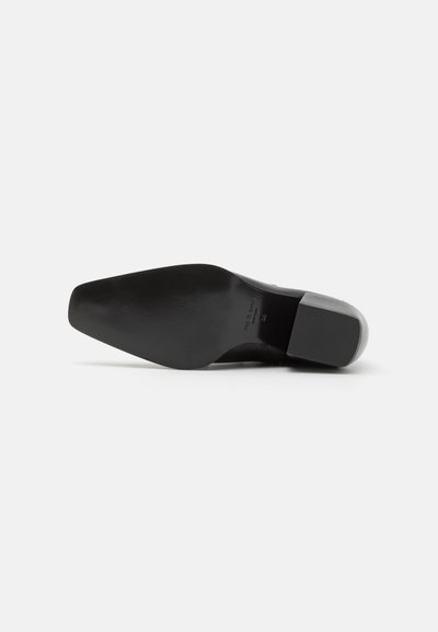 Talpa de pantof din piele neagră, formă ascuțită, textură netedă, detaliu subtil de branding, construcție solidă, cu un călcâi ușor și vârf rotunjit.