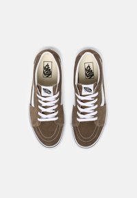 Baskets en daim marron avec lacets blancs, bande latérale blanche et semelle en caoutchouc contrastante. Comprend des accents cousus et un logo sur la languette.