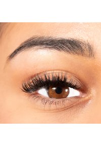 Close-up of a brown eye with long, black eyelashes, a neatly shaped eyebrow, and smooth, light-toned skin around the eye.