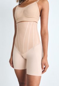 Shapewear beige sans couture comprenant un haut court avec fronces, un short taille haute et des accents à rayures verticales pour un détail de design supplémentaire.