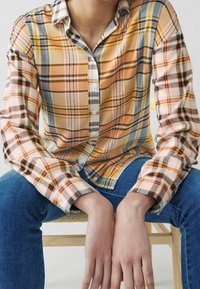 Camicia a quadri nei toni dell'arancione, giallo e blu, con chiusura a bottoni, maniche lunghe e vestibilità comoda, realizzata in tessuto texturizzato.