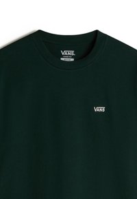Tmavě zelené volné tričko vyrobené z bavlny, s kulatým výstřihem. Na levé hrudi se nachází malé bílé logo "VANS".