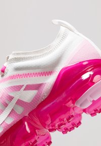 Scarpe da ginnastica bianche con dettagli rosa. Parte superiore traslucida, superficie testurizzata e spessa suola in gomma rosa con unità d'aria visibili.