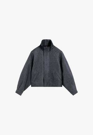 Mørkegrå uldjakke med høj krave, frontflaplukning, skrå sidelommer og lange ærmer med manchet.