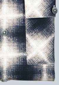 Blau- und cremefarbenes karierter Flanellstoff mit glatter Textur, ausgestattet mit einem Knopfdetail und einer Klappentasche auf der linken Seite.