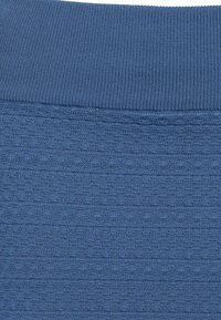 Blauer Stoff mit einem gerippten Taillenbund und einem strukturierten Muster über die gesamte Fläche. Das Material scheint weich und leicht dehnbar zu sein.