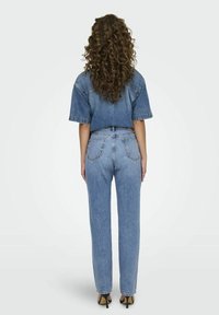 Conjunto de denim que incluye una blusa de manga corta y unos jeans de cintura alta, ambos en azul claro. Corte recto, tela texturizada con costuras visibles.