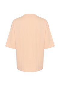 T-shirt à coupe décontractée en coton pêche clair, col rond, manches courtes et ourlet cousu. Texture lisse avec un design simple.