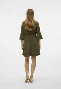 Olivine spalvos suknelė su trims ketvirčiais raukšlėmis, prisiūta juosmens dalimi ir A formos dizainu. Lygus audinys, siekiantis vidurinę šlaunies dalį.