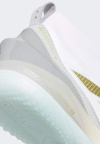 Zbliżenie na tył białego sportowego buta Adidas Adizero Impact+ z amortyzacją Lightstrike Pro oraz przejrzystą teksturowaną podeszwą.