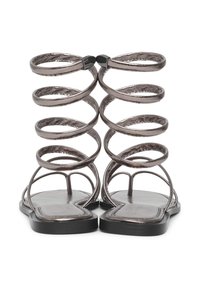 Metallisch graue Gladiatorsandalen mit spiralförmigen Riemen, flacher Sohle und minimalistischem Design, geeignet für Freizeitkleidung.