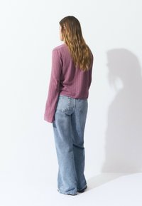 Light purple, textured knit sweater with long sleeves, paired with loose-fitting blue jeans. The jeans have a traditional five-pocket design.