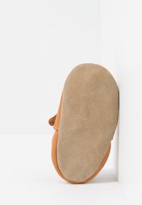 Brune lærersko med en ruskindsbeige såle, avrundet form og justerbar stropp. Sålen er teksturert for grep og holdbarhet.