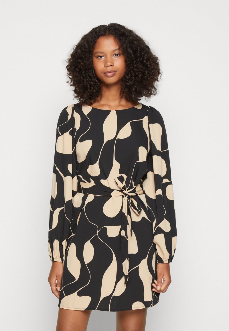 Vestido preto com um padrão abstrato bege, mangas longas, decote redondo e um detalhe na cintura amarrado. Tecido suave com um corte solto.