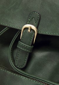 Green faux leather bag featuring a gold buckle closure, contrasting stitching, and smooth texture with a slight sheen.