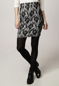 Tight svart och vit kjol med ett ormskinnsmönster, tillverkad av texturerad tyg. Bärs med svarta strumpbyxor och ankelstövlar.