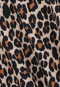 Tissu en imprimé léopard avec des taches noires et brunes sur un fond beige, texture lisse et tombé fluide. Adapté pour diverses utilisations vestimentaires.