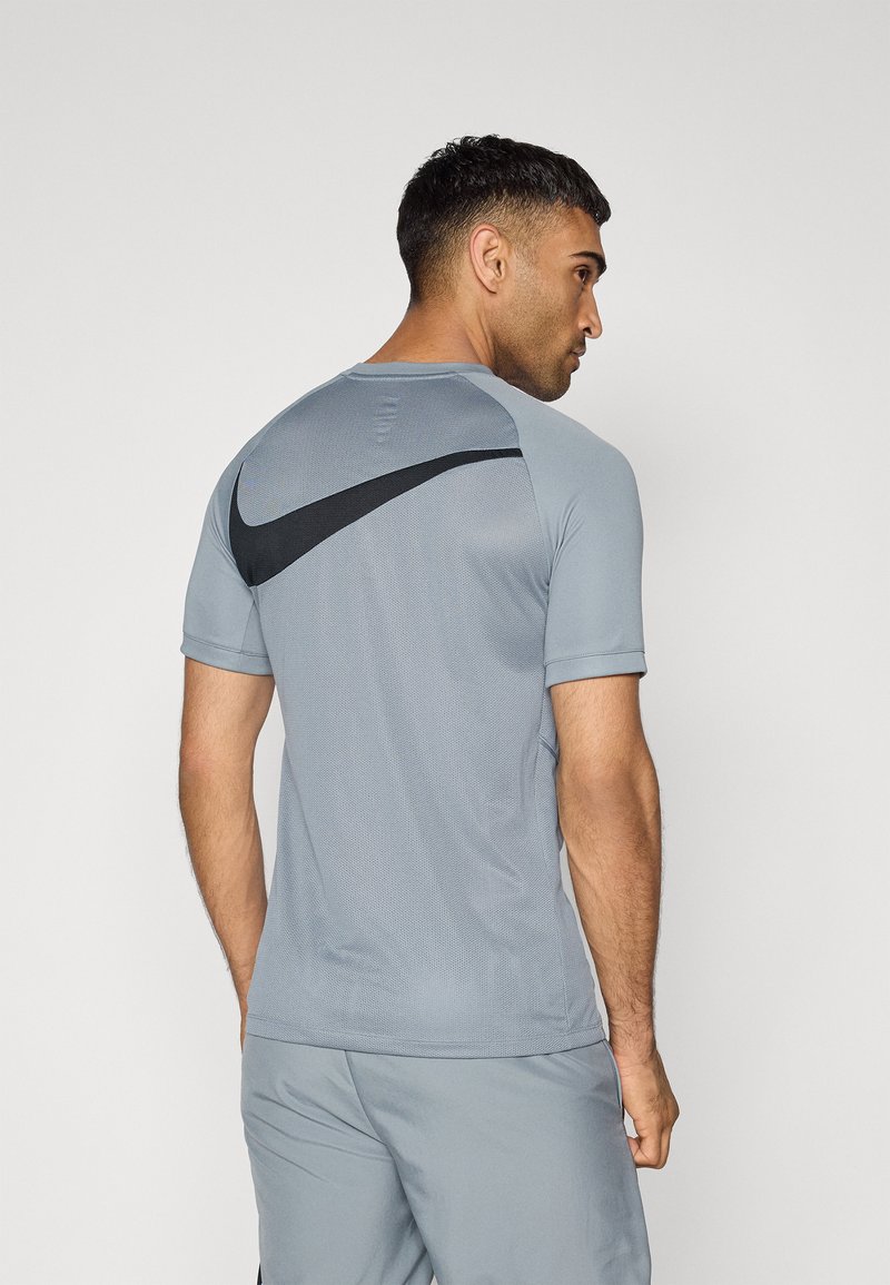 Hallide hallide Nike sportpaita lühikeste varrukatega, mis on varustatud hingava tekstuuriga ja musta logo aktsendiga seljaosas.