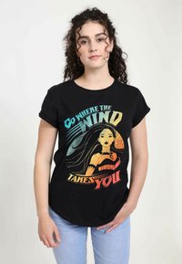 Sort bomulds t-shirt med et farverigt grafisk design med teksten "Gå, hvor vinden tager dig" og en illustreret figur i midten.