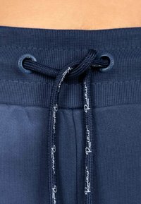 Marineblauwe trainingsbroek met een textuur in de tailleband, voorzien van een koord met contrasterend wit merk en oogjes voor een stevige aanpassing.