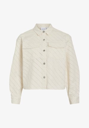 Kortärmad krämfärgad skjorta med knappar, tillverkad av strukturerad tyg med diagonala utskärningsmönster. Har två bröstfickor och knappar i silverfärg.