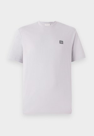 Light lavender short-sleeve t-shirt made of cotton with a round neck and a small dark logo patch on the left chest. Smooth texture.