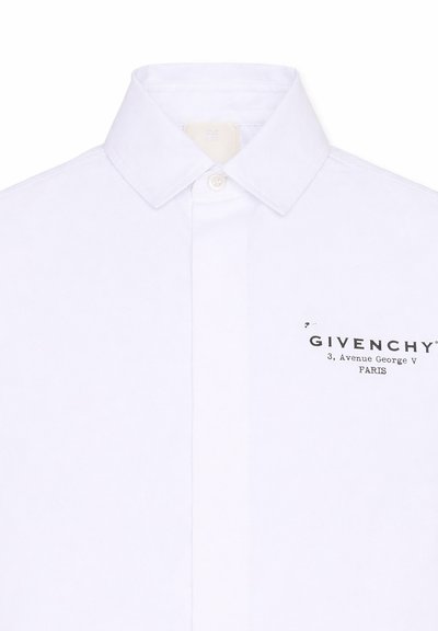 Chemise blanche boutonnée avec col pointu présentant le logo noir Givenchy et l'adresse de Paris sur la poitrine gauche.