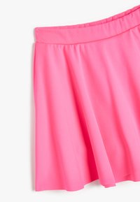 Mini falda rosa con una textura suave y una cintura elástica, que presenta un diseño fluido y una forma simple en A.