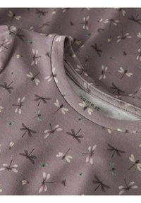 Tissu violet avec un motif de libellule en accents rose pâle, vert et bleu. Vue rapprochée du col et des détails de texture.