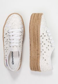 Hvide canvas sneakers med blomsterbroderi, der har en tyk jute-platformsål og hvide snørebånd. Holdbar konstruktion og struktureret overflade.