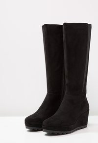 Mustat mokkanahkasaappaat, joissa on polvipituisuus ja korkeat wedget. Varusteena sivuvetoketju ja tekstuuripintaiset kumipohjat. Liukas pinta ja tyylikäs muotoilu.