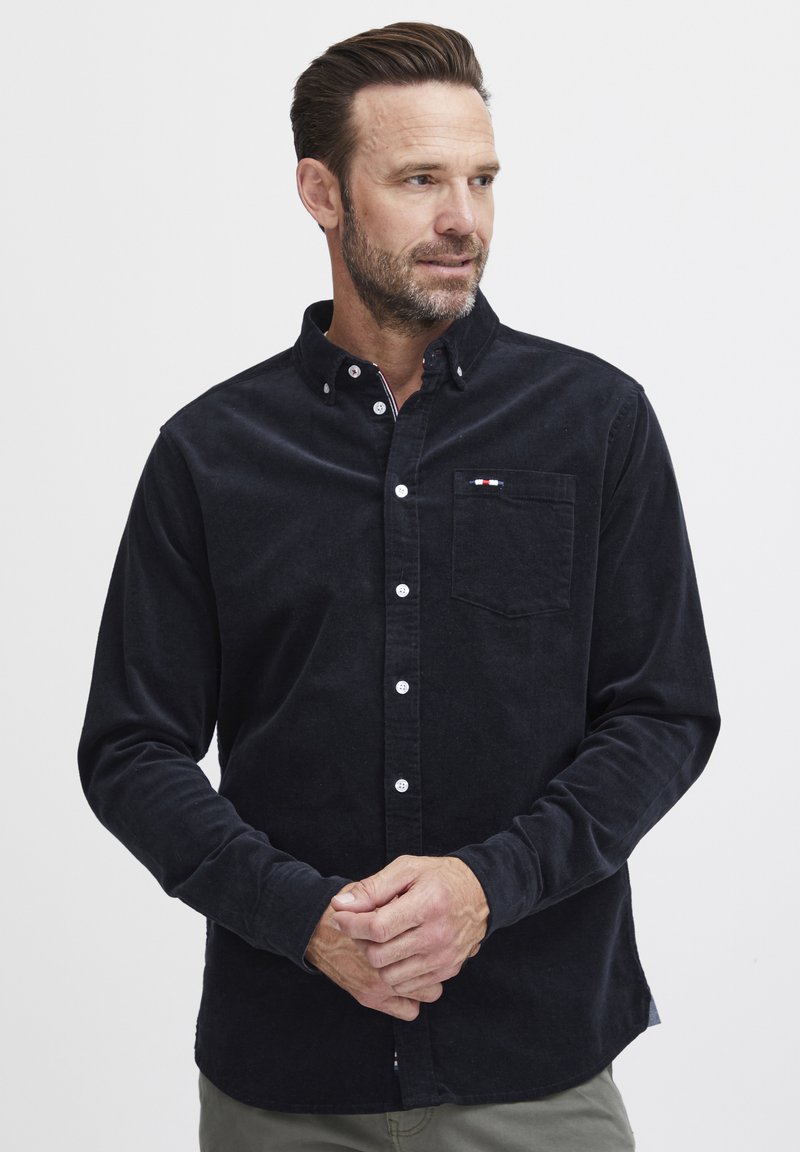 Marine knapper skjorte laget av kordfløyelstoff, med en brystlomme med en liten rød, hvit og blå logodetalj. Lange ermer.