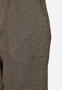 Šedé rebrované pletené jogger nohavice s diskrétnou výšivkou loga, hladkou textúrou a bočnými vreckami pre praktickosť.