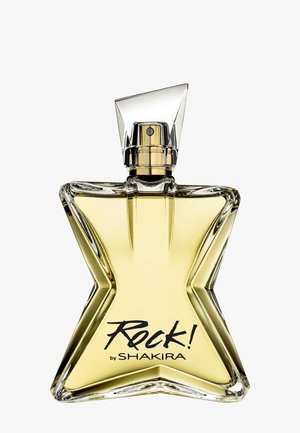 Flacon de parfum en verre en forme d'étoile rempli d'un liquide jaune étiqueté « Rock! by Shakira » avec un capuchon spray angulaire transparent.