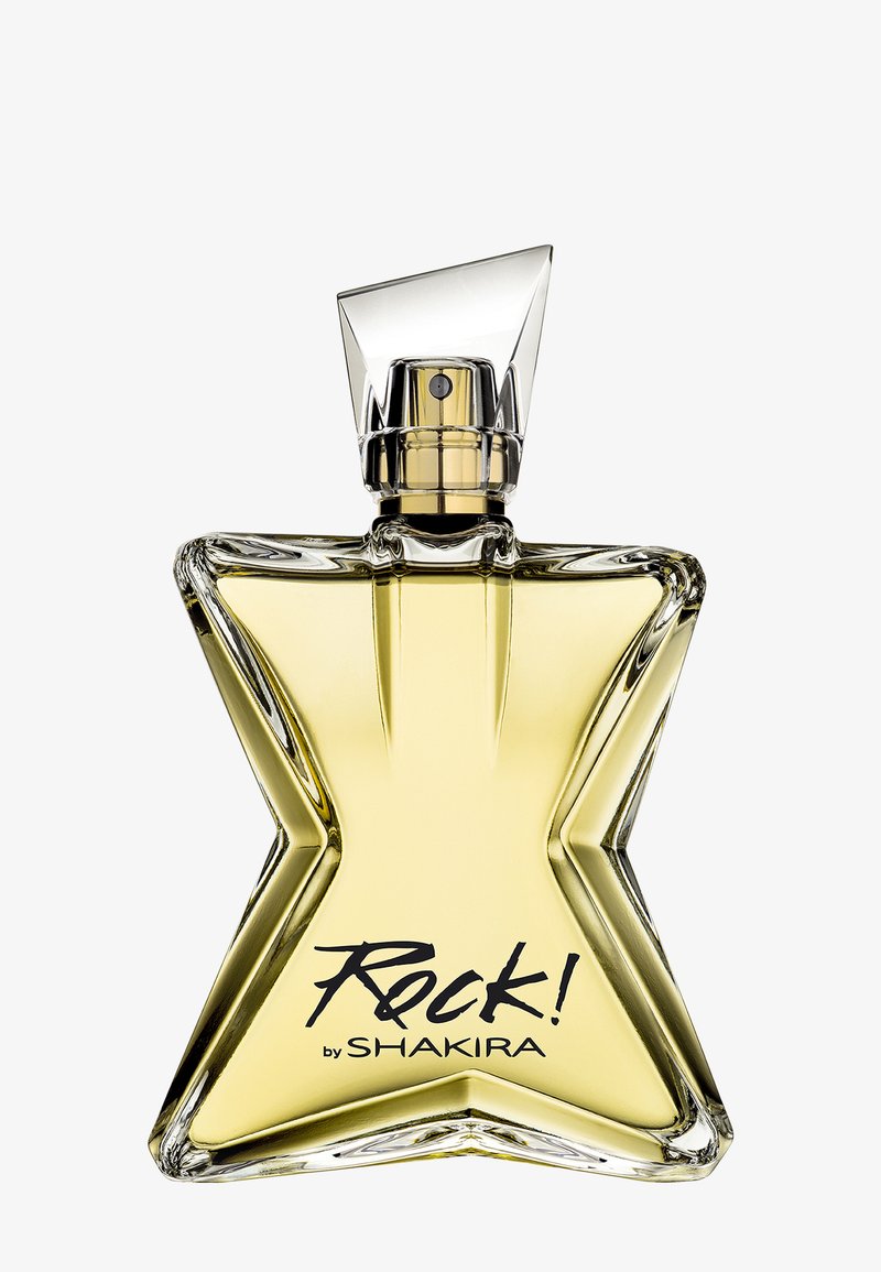 Stervormige glazen parfumfles gevuld met gele vloeistof, gelabeld "Rock! by Shakira" met een heldere hoekige spraydop.