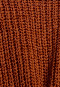 Textured knit fabric in deep orange with a zigzag pattern and raised stitches, featuring a soft, warm appearance.