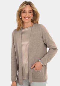 Hellbrauner Cardigan aus weichem Material mit offenem Frontbereich, zwei Taschen und gerippten Bündchen, getragen über einem satinierten beigen Top.