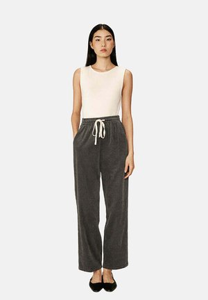 Haut sans manches de couleur beige clair associé à un pantalon de jogging en velours côtelé gris foncé, doté d'une taille élastique et d'un cordon de serrage. Le pantalon présente une finition texturée.